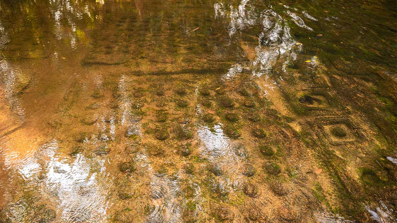 Carved lingas in river at Kulen